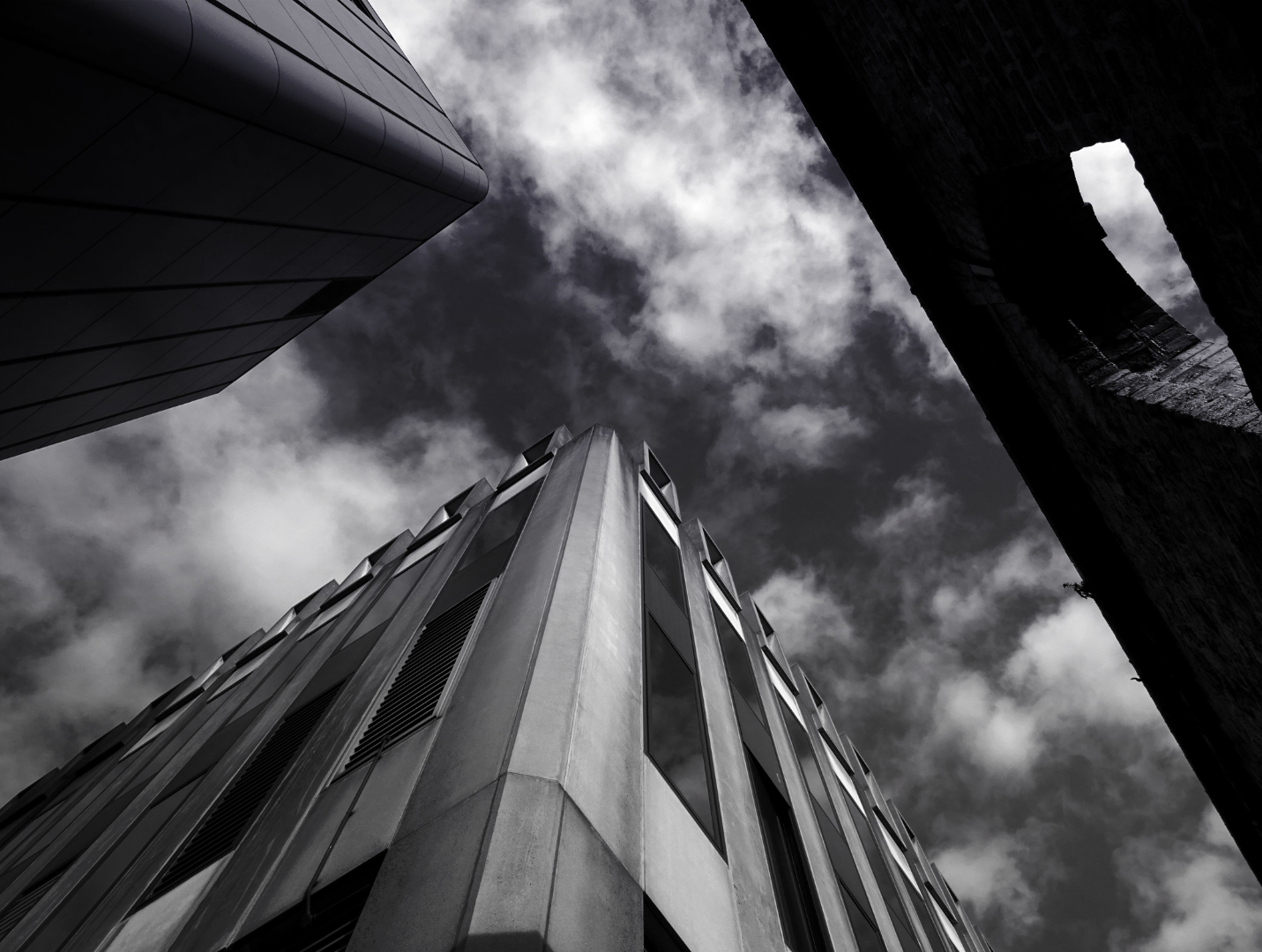 Architecture rising into a clouded sky, black and white